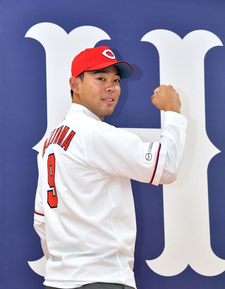 　カープのユニホームに袖を通し気合を見せる秋山（撮影・立川洋一郎）