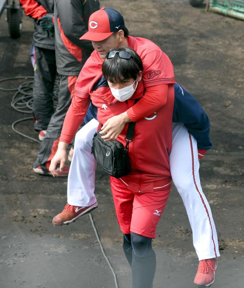 　打撃練習で打球を足に当て、おんぶされながらベンチへ引き揚げる河野