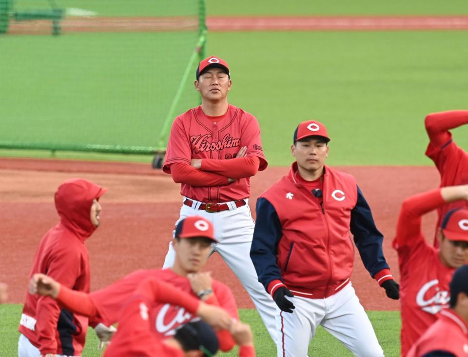 　ウオーミングアップをする選手の後ろで、目を閉じて思いをはせる新井監督（撮影・田中太一）