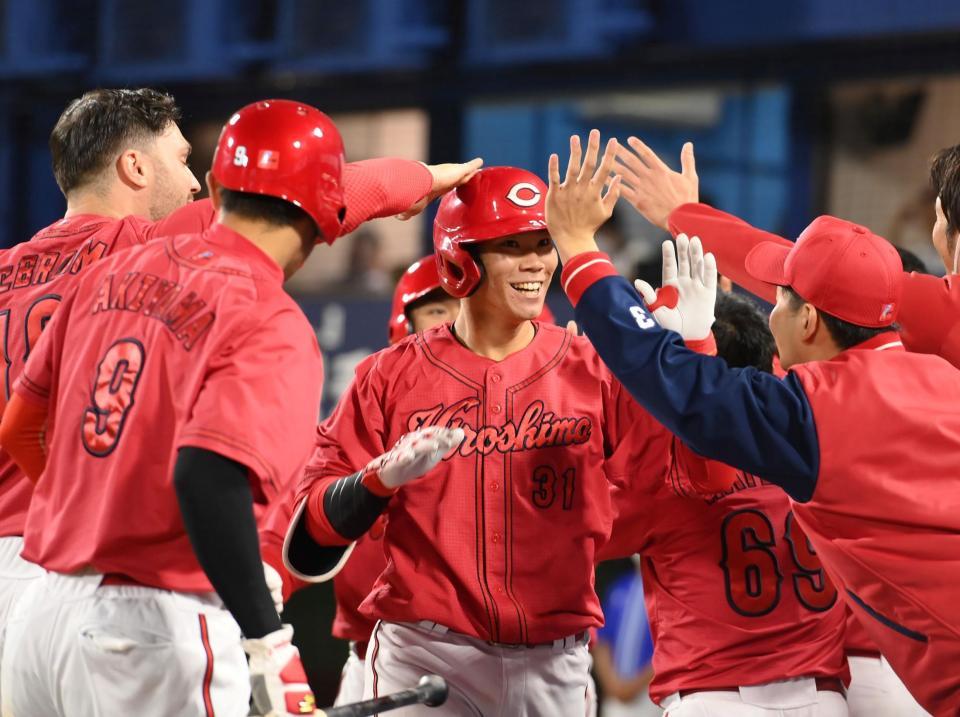 　９回、右中間へ満塁本塁打を放ち、ナインに迎えられる坂倉（中央）＝撮影・伊藤笙子