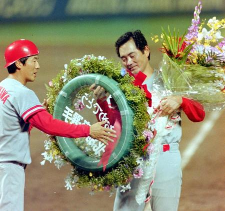 ２００勝をマークし、達川（左）から花束を贈られる北別府さん＝１９９４年７月