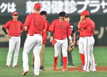 　６回、ブリンソンの遊ゴロで一塁へ送球する際にベースで足首をひねり、治療に向かう小園（中央）＝撮影・西岡正
