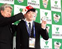 　広島の近藤スカウトから帽子をかぶせてもらうドラフト３位・滝田