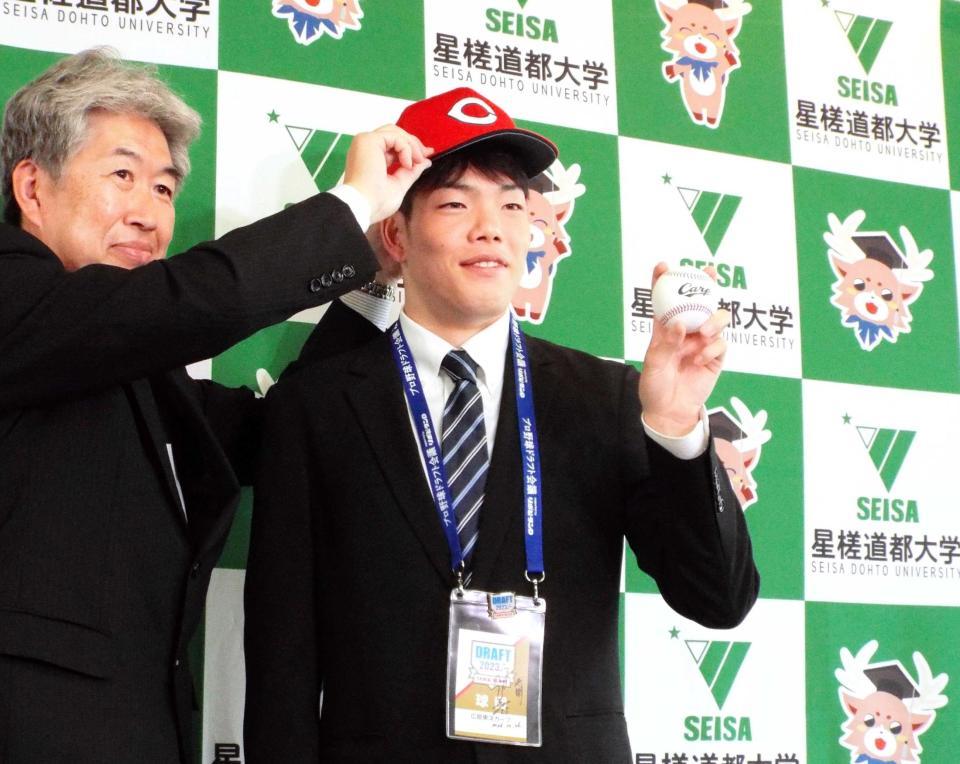 　広島の近藤スカウトから帽子をかぶせてもらうドラフト３位・滝田