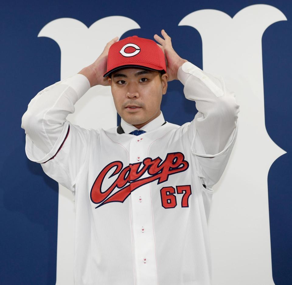 　入団会見でユニホームに袖を通す内間（撮影・田中太一）