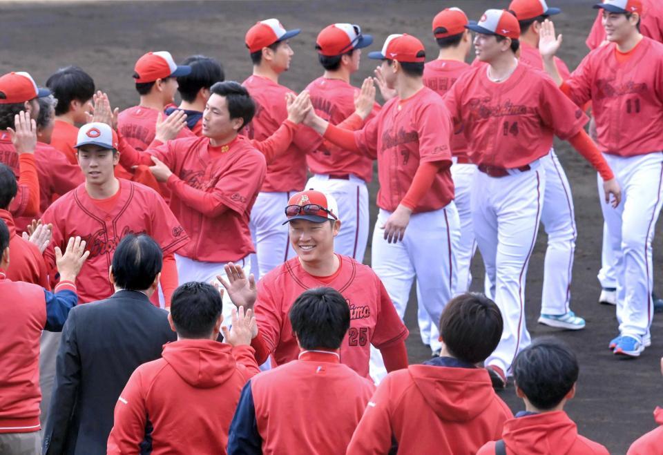 　日南でのキャンプを終え、ナインやスタッフらとタッチを交わす新井監督（中央）＝撮影・市尻達拡