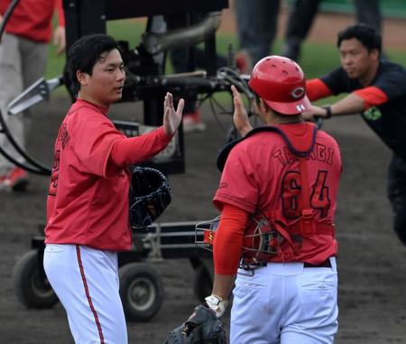 　シート打撃登板を終え、高木とタッチを交わす栗林（撮影・市尻達拡）