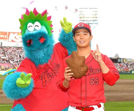 　今季初勝利を挙げ、もみじまんじゅうを手に笑顔を見せる玉村