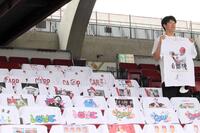 　『自然体』と書かれた自身のＴシャツを持って自然体の表情を見せる野間（撮影・畠山賢大）