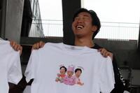 　自身の赤ちゃんに扮（ふん）した姿がプリントされたＴシャツを持ち、同じ顔をする石原（撮影・畠山賢大）