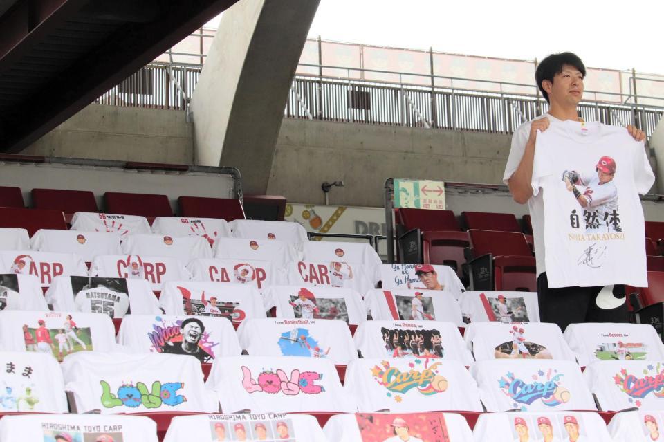 　『自然体』と書かれた自身のＴシャツを持って自然体の表情を見せる野間（撮影・畠山賢大）