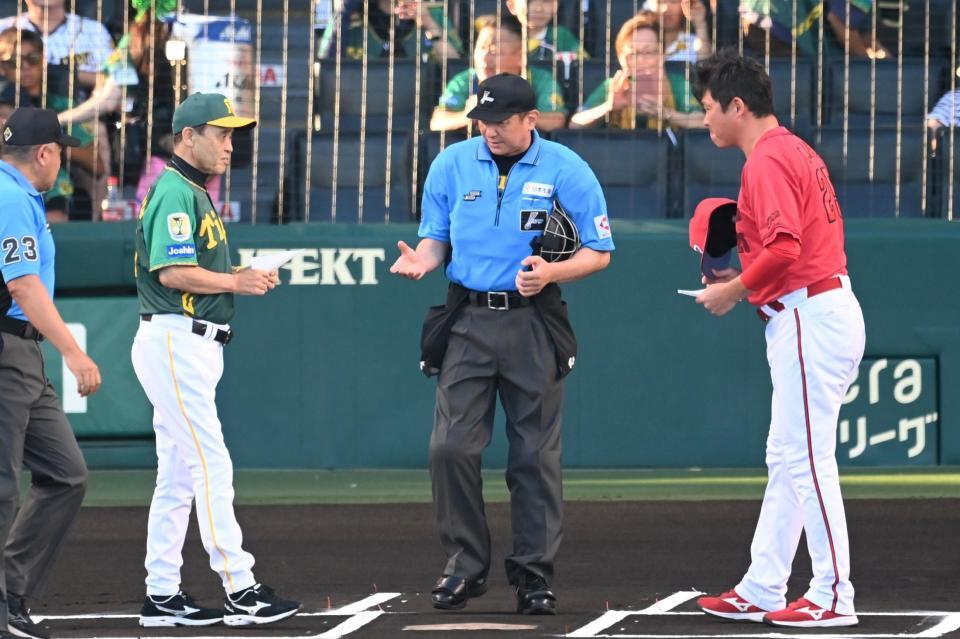 　メンバー表を交換する岡田監督（左）と新井監督（撮影・飯室逸平）