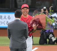 　野球殿堂入りした黒田博樹氏（手前）に花束を贈る新井監督＝２３日