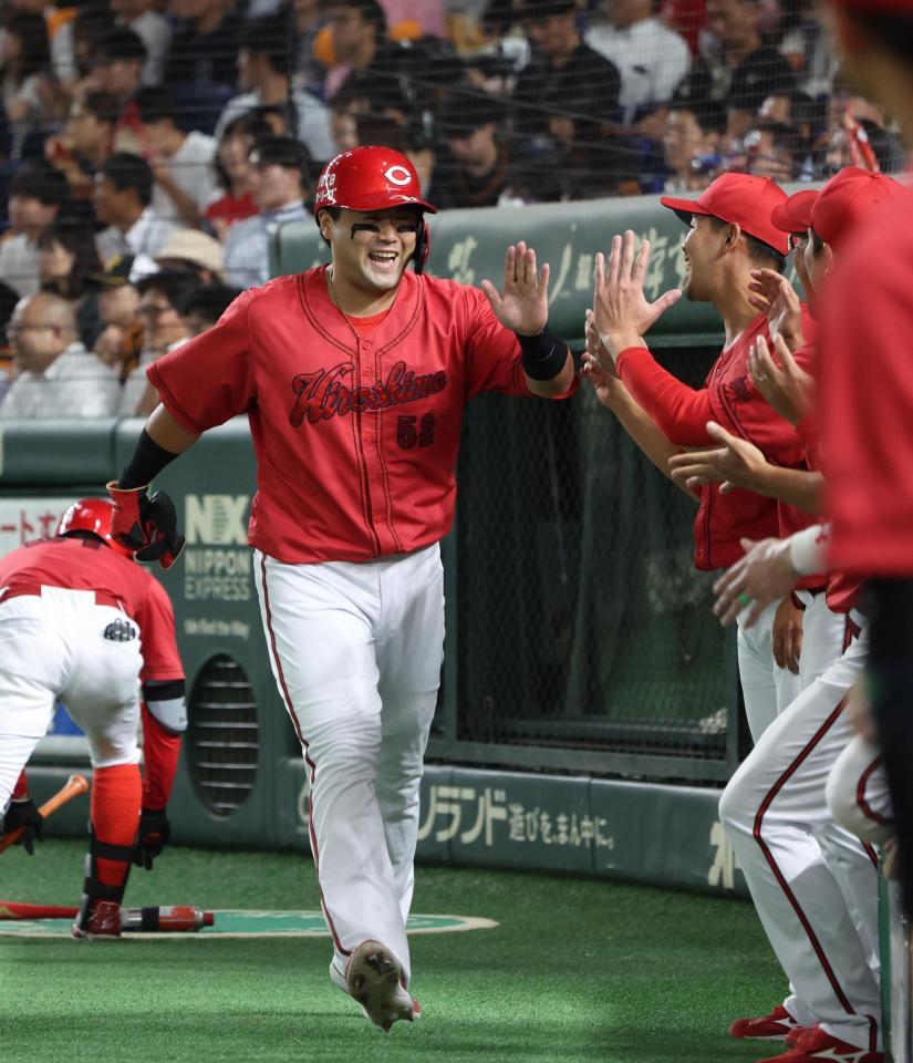 　４回、坂倉の中前適時打で生還しナインに迎えられる末包（撮影・金田祐二）