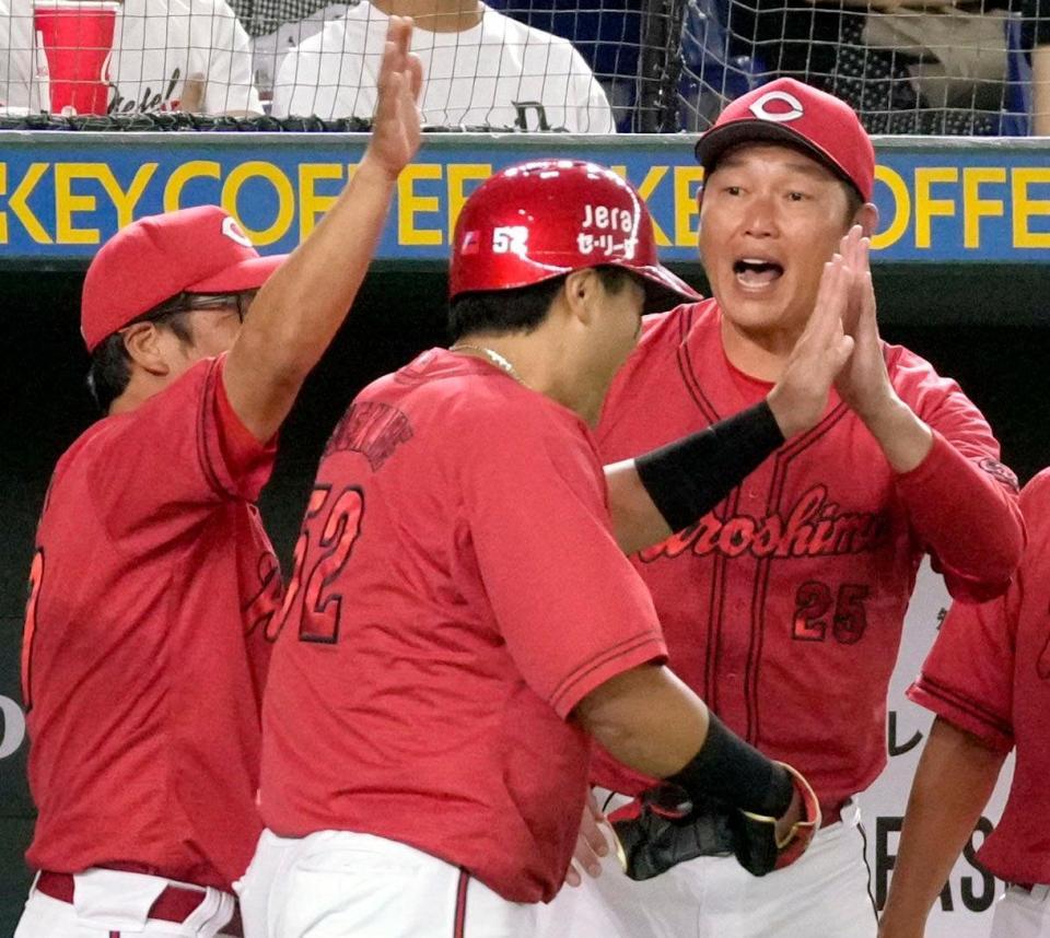 　４回、坂倉の適時打で生還した末包（手前）を迎える新井監督（右）