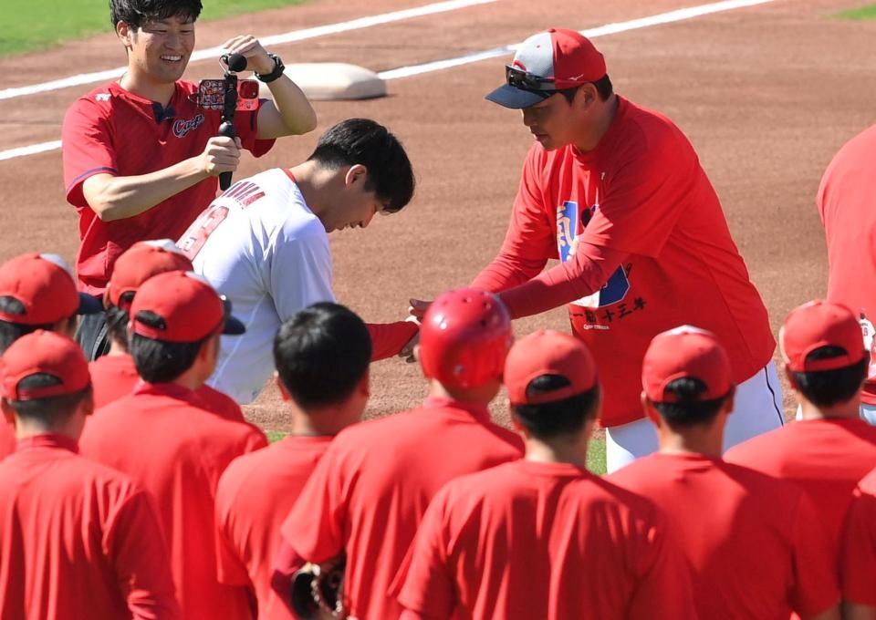 　練習前の円陣で野村は新井監督と握手をする（撮影・市尻達拡）