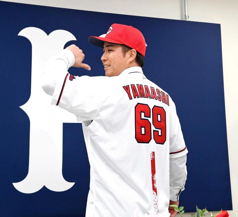 　新しいユニホームに袖を通しポーズを決める山足（撮影・市尻達拡）