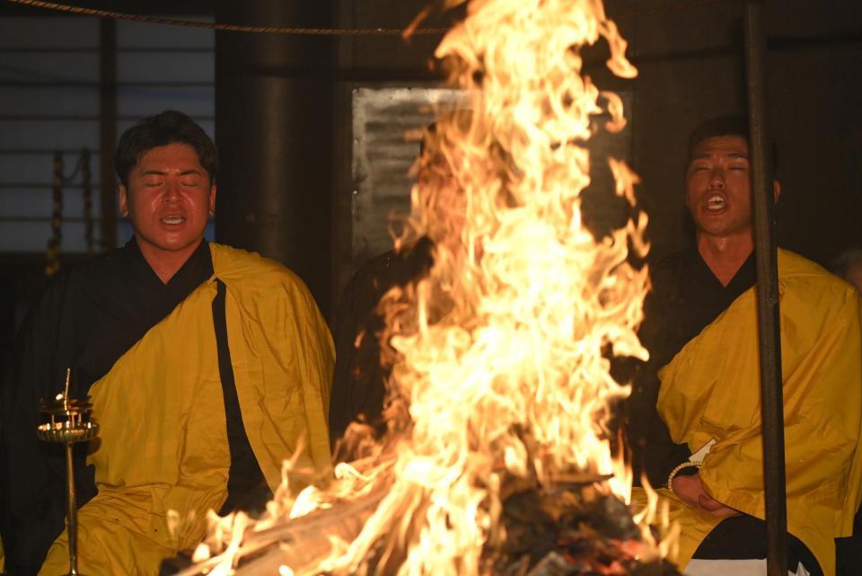 　火柱の前で経を唱える会沢（左）と中村奨（撮影・市尻達拡）