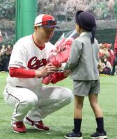 　歓迎セレモニーで園児から花束を受け取る新井監督