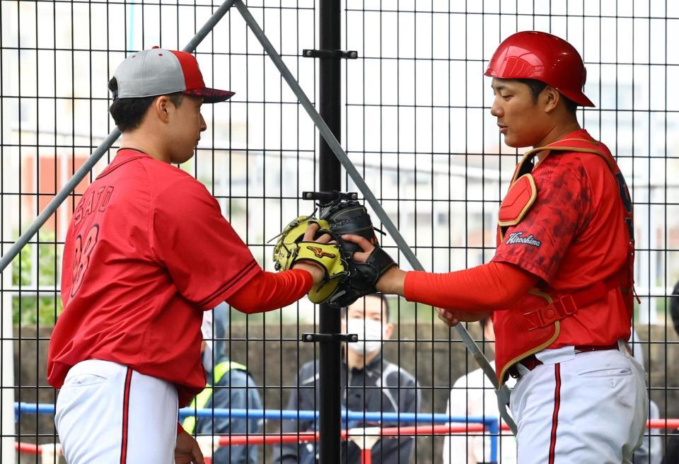 　ブルペンで投球練習を終えた佐藤柳（左）は渡辺とグラブタッチする（撮影・山口登）