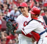 　巨人戦で完封して今季初勝利を挙げ、捕手石原（右）と喜ぶ床田
