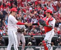 　今季初勝利を完封で飾り、石原と握手する床田（撮影・市尻達拡）
