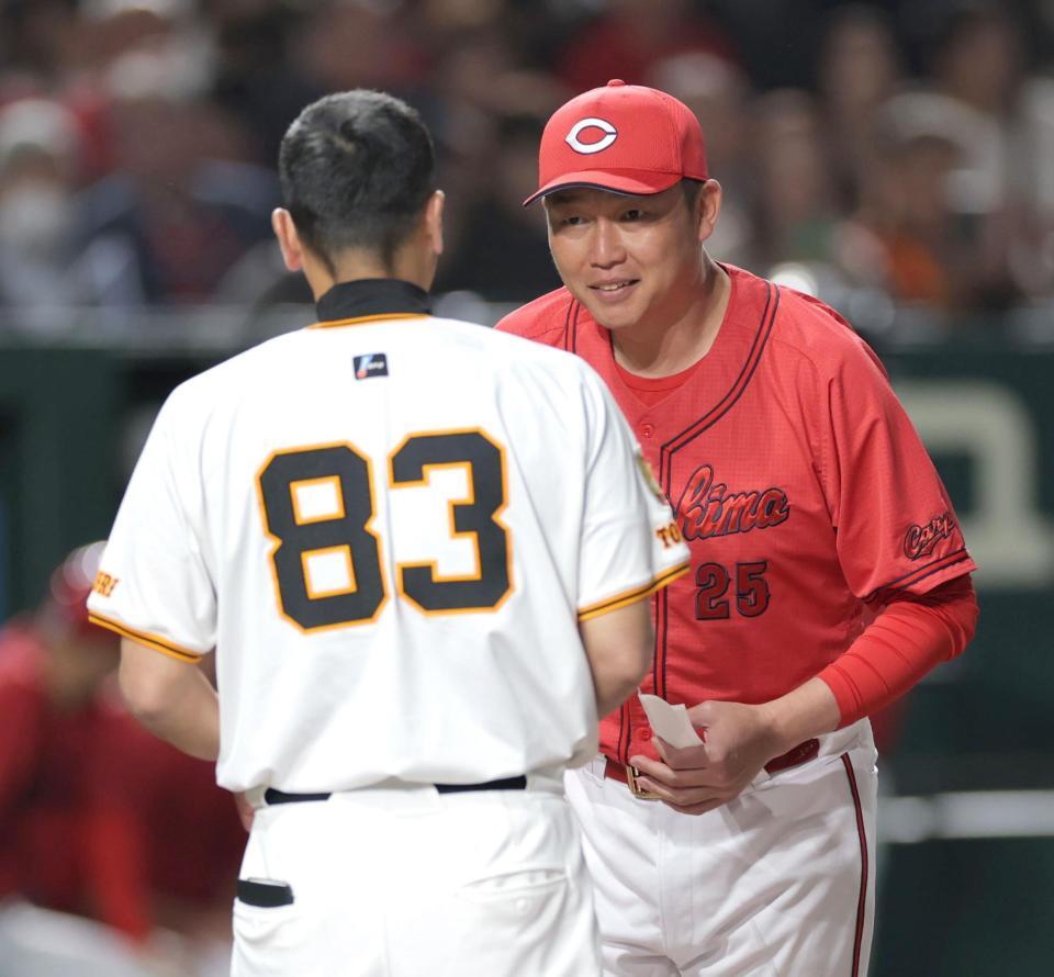 　メンバー表交換で阿部監督（手前）と話す新井監督（撮影・西岡正）