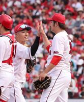 　勝利のタッチで、床田と手を合わせる中村奨（撮影・市尻達拡）