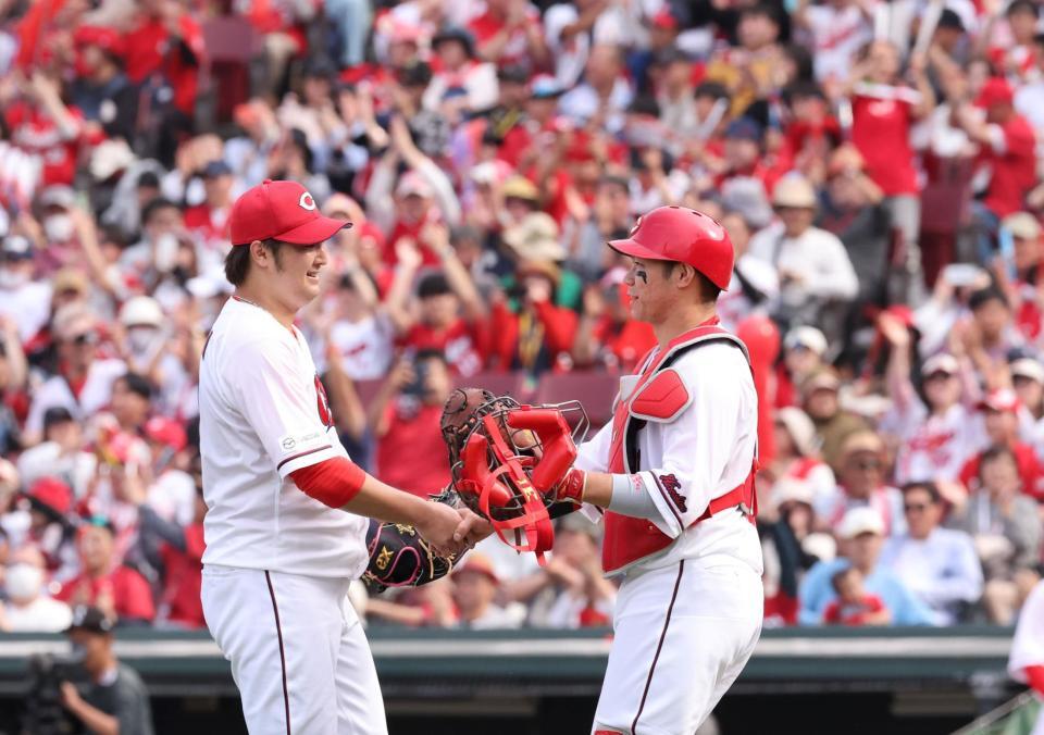 　完封勝利でチームの連敗を止め、坂倉と握手を交わす床田（撮影・市尻達拡）