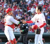 　９回、無失点で締め、坂倉（左）と握手をする栗林（撮影・市尻達拡）