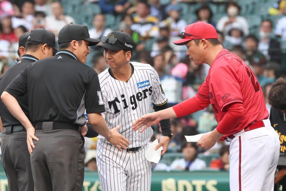 　メンバー表交換を終え、審判団と握手を交わす藤川監督と新井監督（右）＝１７日