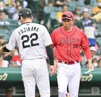 　１７日の試合前は互いに目を合わさずメンバー表の交換を行う新井監督（右）と藤川監督