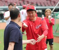 　見学するファンとの記念写真に入るよう、河内広報（左）を指名する新井監督（撮影・坂部計介）