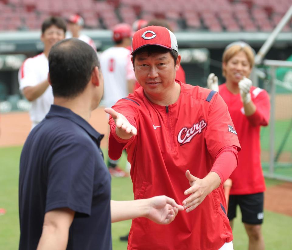 　見学するファンとの記念写真に入るよう、河内広報（左）を指名する新井監督（撮影・坂部計介）