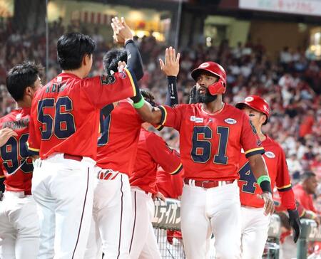 　６回、小園の左越え２点タイムリー二塁打で生還し、タッチを交わすアメフト風ユニホームを着たファビアンら（撮影・市尻達拡）