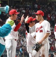 　中村奨（右）とタッチを交わす新井監督（撮影・市尻達拡）