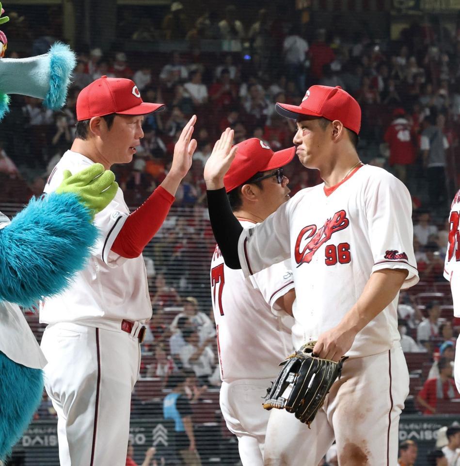 　中村奨（右）とタッチを交わす新井監督（撮影・市尻達拡）