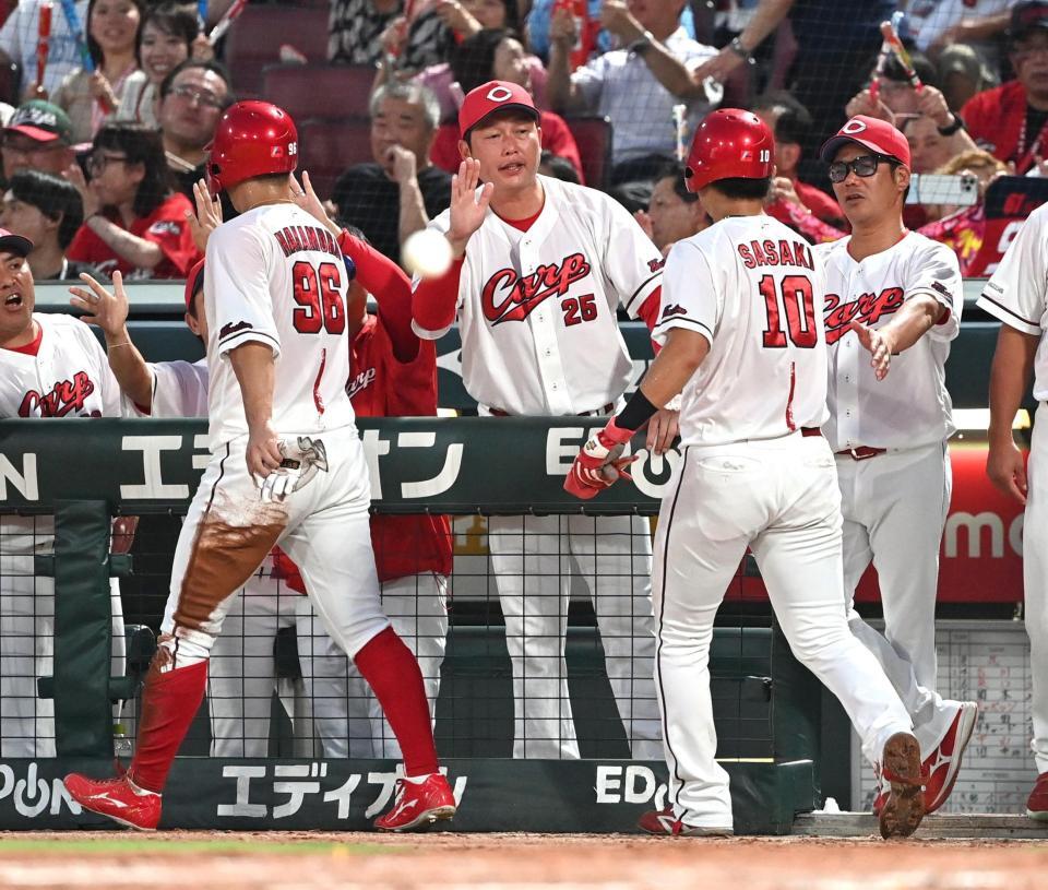 　２回、ファビアンの２点適時打で生還した二走・中村奨と三走・佐々木を迎える新井監督（中央）