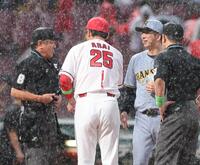 　どしゃ降りの中、メンバー表を交換する新井監督と藤川監督（撮影・市尻達拡）