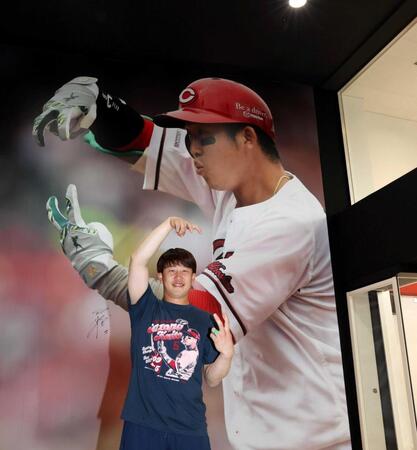 　巨大ポスターと同じポーズをとる小園（撮影・市尻達拡）