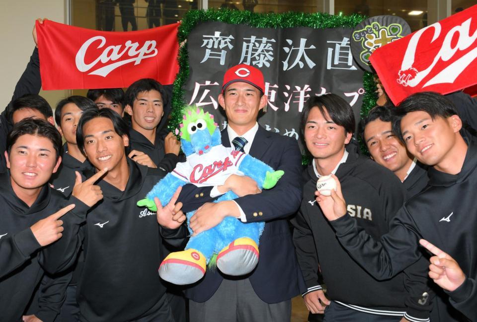 　広島に２位指名され、スラィリー人形を抱きしめる亜大・斉藤汰直（中央）＝撮影・伊藤笙子