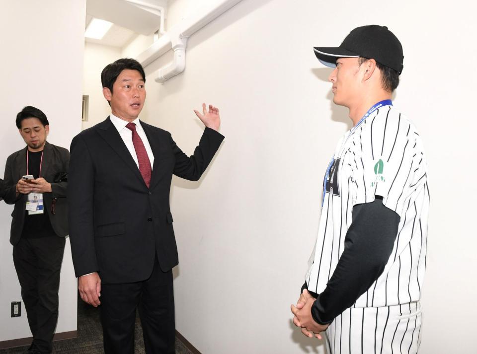 　仙台から東京に移動し亜大・斉藤汰直（右）と話す新井監督（撮影・佐藤厚）