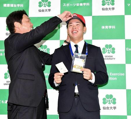 　新井監督（左）から帽子をかぶせてもらい笑顔の平川（撮影・開出牧）