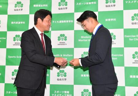 　新井監督（左）からドラフト会議で引いた当たりクジをプレゼントされ感激の１位指名の仙台大・平川蓮（撮影・開出牧）