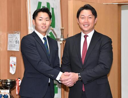　指名あいさつに訪れた新井監督（右）と握手をかわす１位指名の仙台大・平川蓮（撮影・開出牧）
