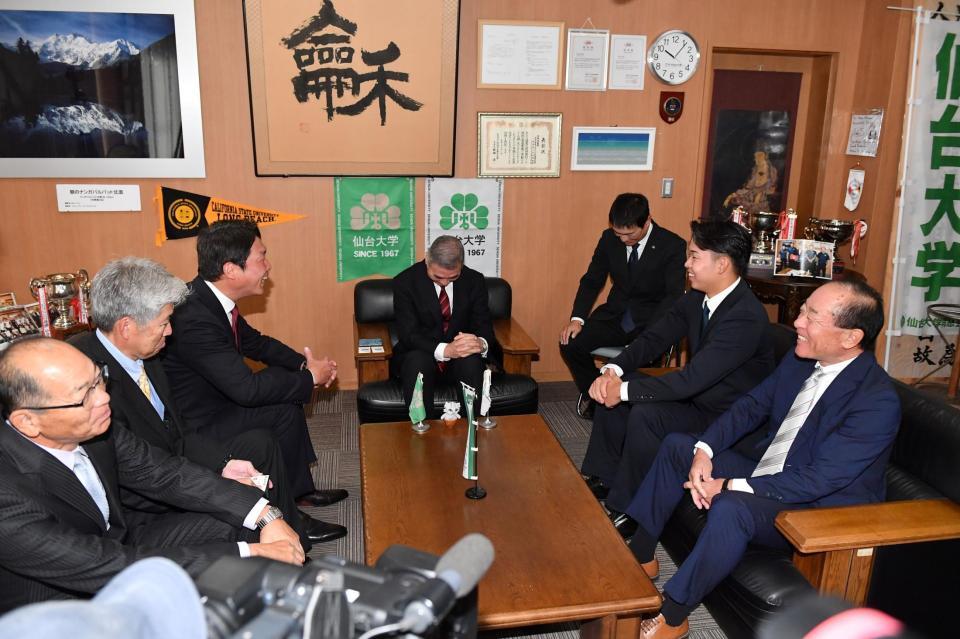 　指名あいさつに訪れた新井監督（左手前から３人目）と学長室で談笑する１位指名の仙台大・平川蓮（右手前から２人目）＝撮影・開出牧