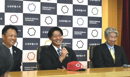 　会見で笑顔を見せる北海学園大・工藤（中央）、左は同大の島崎監督、右は担当の近藤スカウト