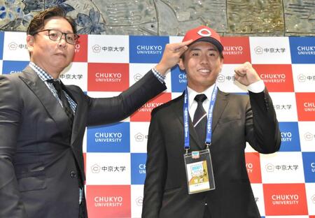 　松本スカウト（左）から帽子をかぶせてもらい、笑顔の中京大・高木