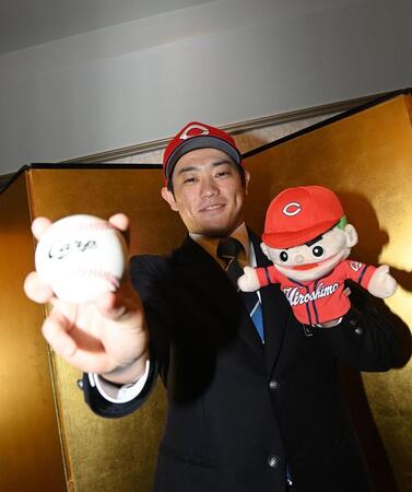 　仮契約を終え、広島グッズを手にポーズを決める近大・勝田成（撮影・西田忠信）