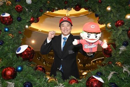 　仮契約を終え、広島グッズを手にポーズをとる近大・勝田（撮影・西田忠信）